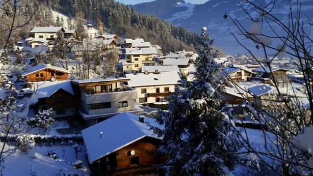 A snow-covered village with multiple buildings, including modern and traditional houses, surrounded by trees and mountains. - Spacious House In Fugen With Terrace (Fuegen)