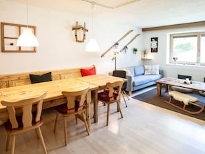 A cozy living room with a wooden bench, a sofa, a dining table with chairs, and a fireplace. - Spacious House In Fugen With Terrace (Fuegen)