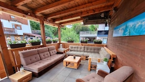 A covered patio area with wooden furniture, including sofas and a coffee table, and potted plants. - Spacious House In Fugen With Terrace (Fuegen)