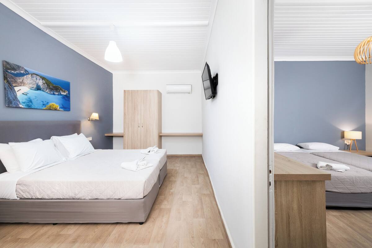 Et moderne hotelværelse med en stor seng, et skrivebord og et fjernsyn ophængt på væggen.