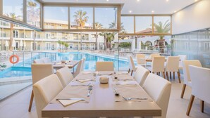 A poolside dining area with tables set for six, overlooking a pool and a building with balconies. - Cameo Beach Resort (Zakynthos)