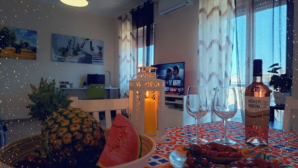 A dining table with a pineapple, watermelon, and a bottle of rosato di primitivc. - The House OF THE SUN Brindisi (Brindisi)