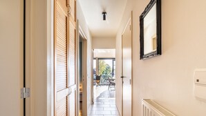 Un pasillo con puertas correderas de madera, un radiador y un espejo en la pared.