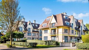 Una hilera de edificios residenciales modernos con un patio central, que presenta una combinación de fachadas de ladrillo y piedra, múltiples balcones y un espacio verde bien cuidado.