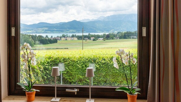 A window with a view of a green field and mountains in the distance. - Holiday Home Attersee Near Hiking Trails (Attersee)