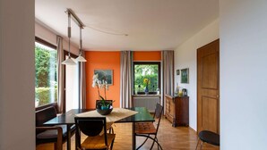A dining area with a table, chairs, and a view of greenery outside. - Holiday Home Attersee Near Hiking Trails (Attersee)