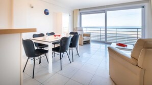 A modern hotel room with a balcony, a dining area with a table and chairs, and a sofa. - Les Petrels 302 on the Beach in Koksijde (Koksijde)