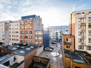 En byggnad med flera våningar som innehåller både bostäder och kommersiella lokaler, med en blandning av olika arkitektoniska stilar och en central innergård där fordon kan parkeras.