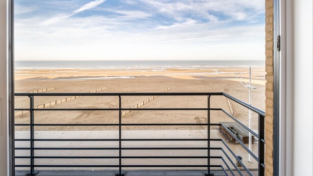 A view from a balcony overlooking a beach with a clear sky. - Les Petrels 302 on the Beach in Koksijde (Koksijde)