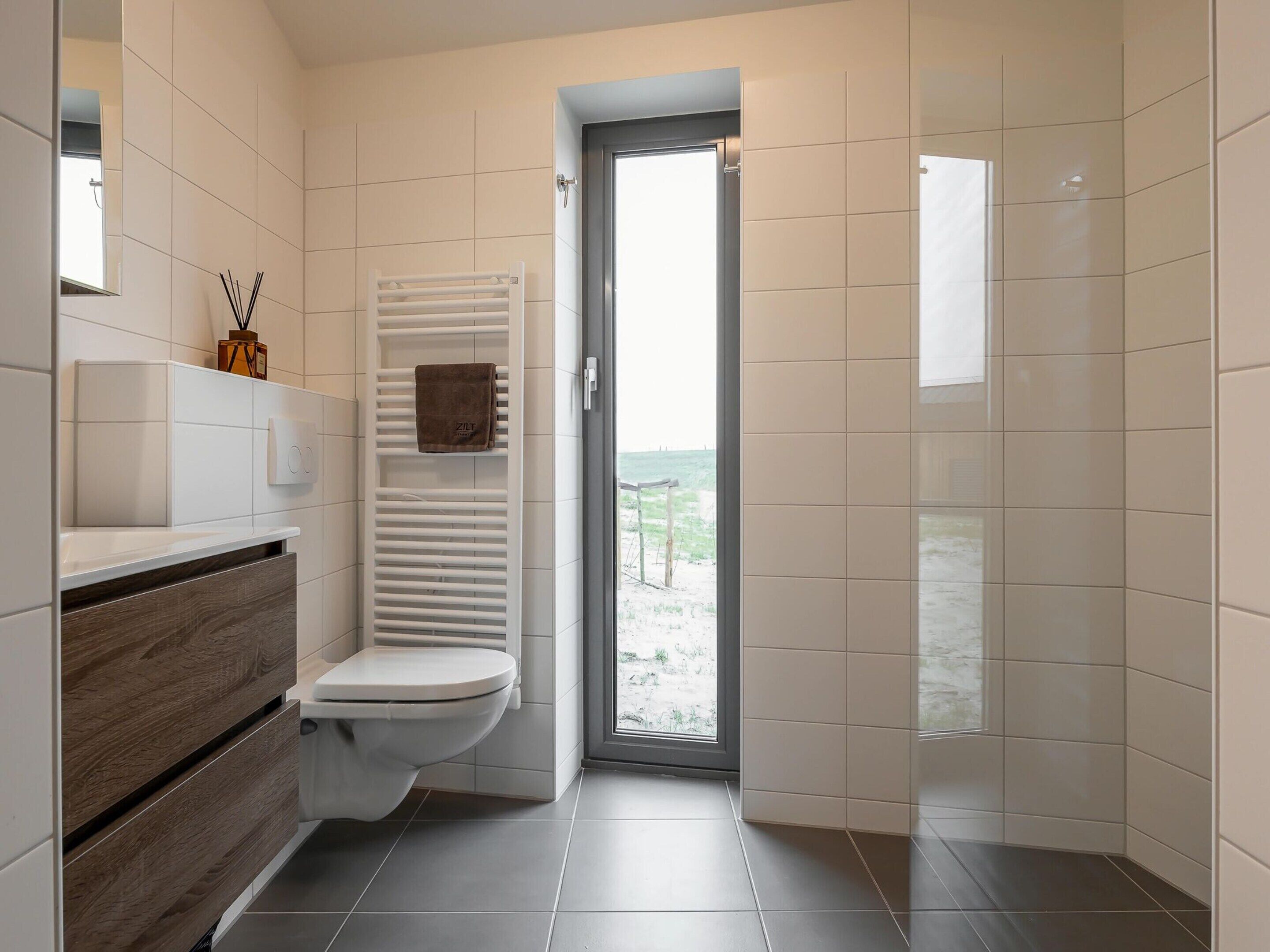 Ein modernes Badezimmer mit Toilette, Handtuchhalter und Duschbereich.