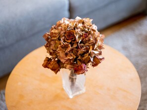 A clear glass vase with dried flowers on a round wooden table. - Cosy Apartment in Koksijde Near the Beach (Koksijde)