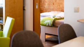 A hotel room with a bed, a wooden door, and a small table. - Cosy Apartment in Koksijde Near the Beach (Koksijde)
