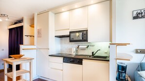 A compact kitchen with white cabinets, a microwave, a dishwasher, and a coffee maker. - Cosy Apartment in Koksijde Near the Beach (Koksijde)