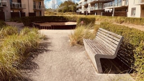 Een pad dat leidt naar een bank in een woonwijk met moderne appartementen.