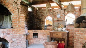 A rustic kitchen with brick walls, a wooden counter, and a hanging basket.