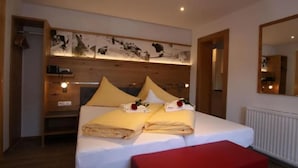 Ein Hotelzimmer mit einem Bett, einer roten Bank, einem Holzkopfende mit Kunstwerk und einem Spiegel an der Wand.