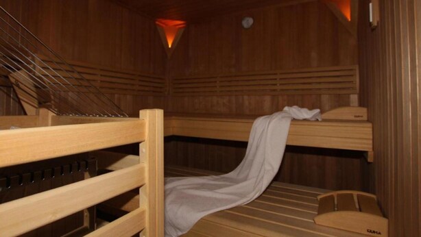 Eine Sauna mit Holzbänken und schrägverdeckter Decke.