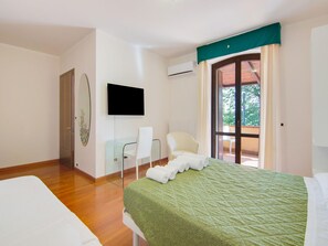 Una habitación de hotel con cama, una silla, televisor y un balcón con vistas.