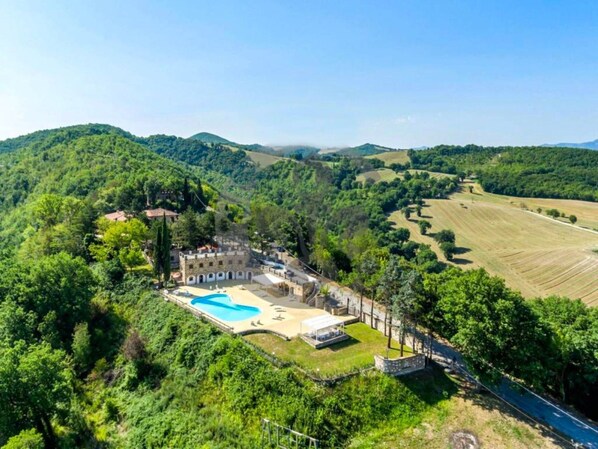 Una villa con piscina rodeada de exuberante vegetación y colinas ondulantes.