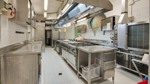Una cocina comercial con electrodomésticos de acero inoxidable, un horno grande y un mostrador para alimentos.
