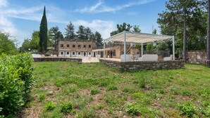 Un patio con un edificio de piedra, mobiliario exterior y una pérgola.