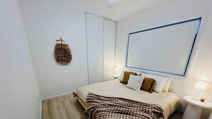 Ein Schlafzimmer mit Bett, Nachttischen, einer hängenden Ampel und einem großen Fenster.