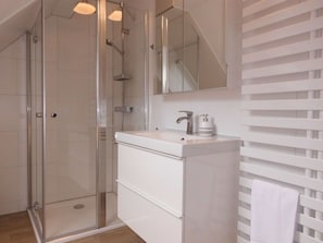 A modern bathroom with a glass shower enclosure, a white sink with a mirror above, and a towel rack. - Holiday Apartment Haus Bodefurt - Apartment 2 (Thale)