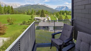 A balcony with a view of a mountainous landscape, a chair, and a small table. - Dachgeschoss-atelier (Seefeld in Tirol)