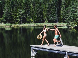 A wooden dock extending into a calm lake surrounded by dense forest.