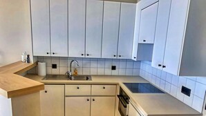 Une cuisine moderne avec des meubles blancs, un évier en acier inoxydable et un plan de travail en bois.