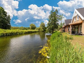 Uitzicht op een rivier met een huis, voorzien van een overdekt terras en een heldere lucht.