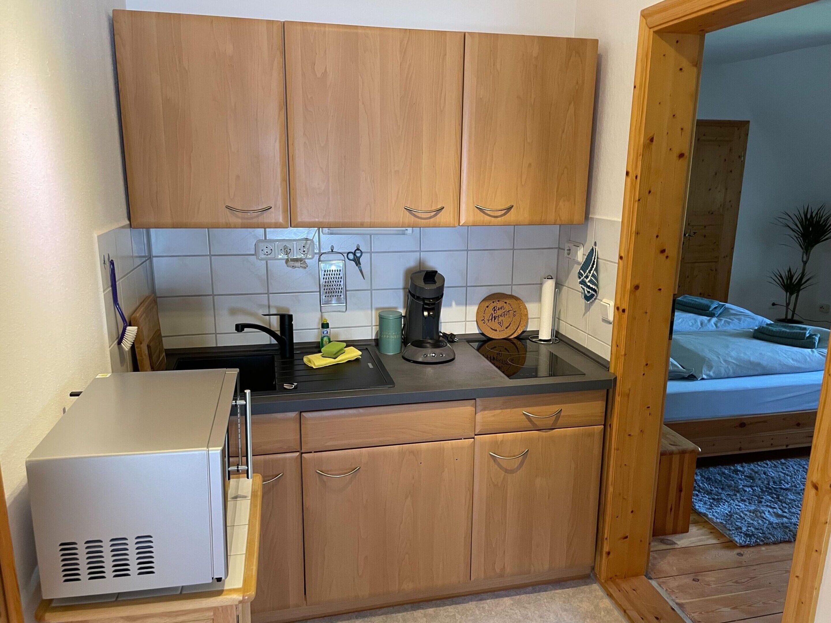 A compact kitchen with wooden cabinets, a built-in microwave, and a coffee maker on the counter.