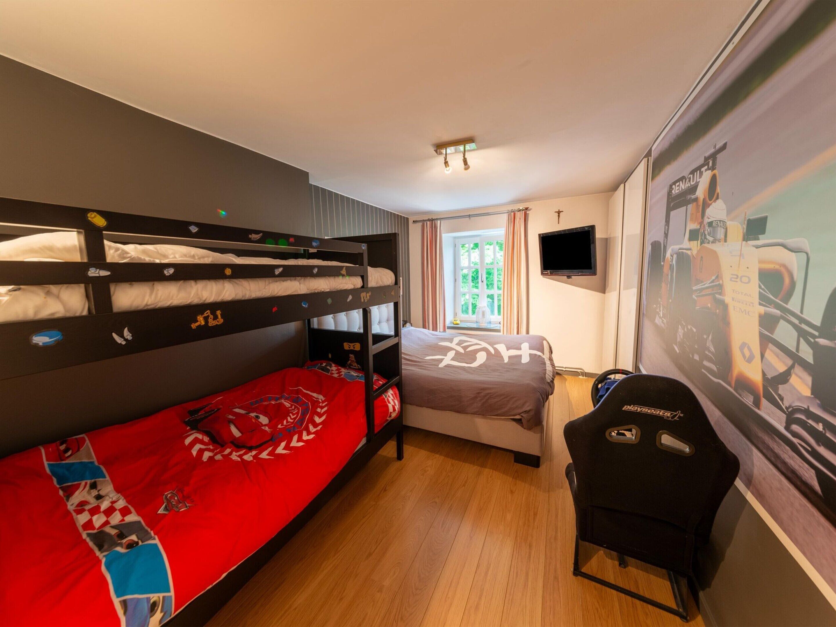 Une chambre avec un lit superposé, un bureau et une télévision.