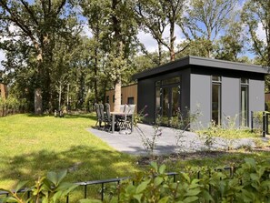 A modern outdoor seating area with a table and chairs, surrounded by a well-maintained lawn and trees. - Apartment in Sonthofen (Zorgvlied)