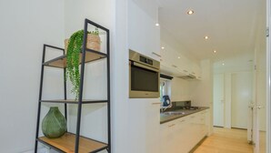 Une cuisine moderne avec des meubles blancs, un four à micro-ondes en acier inoxydable et un plancher en bois.