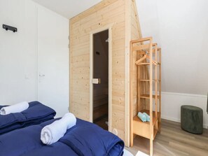A bedroom with a bunk bed, a wooden ladder, a small wooden shelf with towels, and a grey ottoman. - Holiday Home in Simonshaven by Lake Beach (Simonshaven)