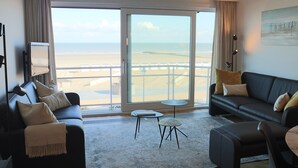 Habitación de hotel moderna con un amplio ventanal corredero que da a un balcón con vistas a la playa.