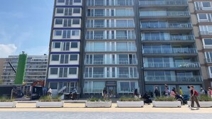 A multi-story residential building with balconies, a visible staircase, and a green construction crane in the foreground. - Apartment in Nieuwpoort With Ocean Views (Nieuwpoort)