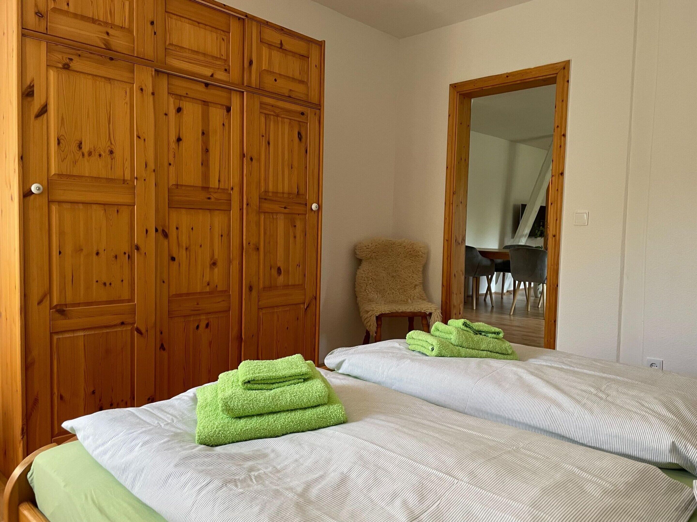 Un dormitorio con dos camas, armario de madera y un espejo.