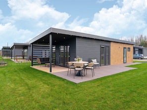 A modern house with a covered patio, outdoor seating, and a car parked nearby.