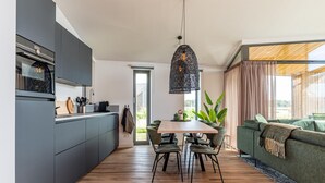 Una cocina moderna con armarios grises, una mesa de comedor de madera y una lámpara colgante.
