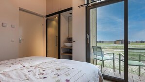 Un dormitorio con una cama grande, un puertas corredera que da a un balcón y vistas al campo.
