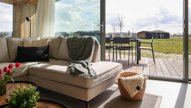 A modern living room with a large glass door leading to an outdoor patio. - Inviting Holiday Home in the Nature (Wissenkerke)