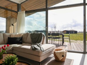 En moderne stue med en stor glasdør, der fører ud til en udendørs terrasse.