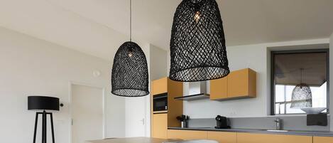 A modern kitchen with a dining table, chairs, and pendant lights.