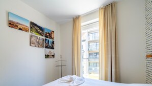 Una habitación de hotel con cama, toallas, una ventana con cortinas y una pared decorada con fotografías de viajes.