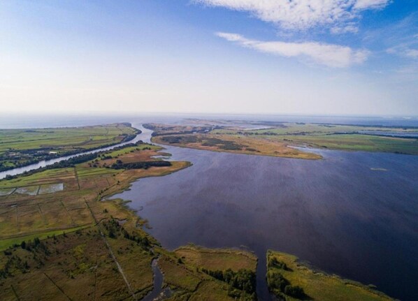 An aerial view of a river winding through a landscape with fields and a distant horizon. - Holiday Home in Grou Near Frisian Lakes (Grou)