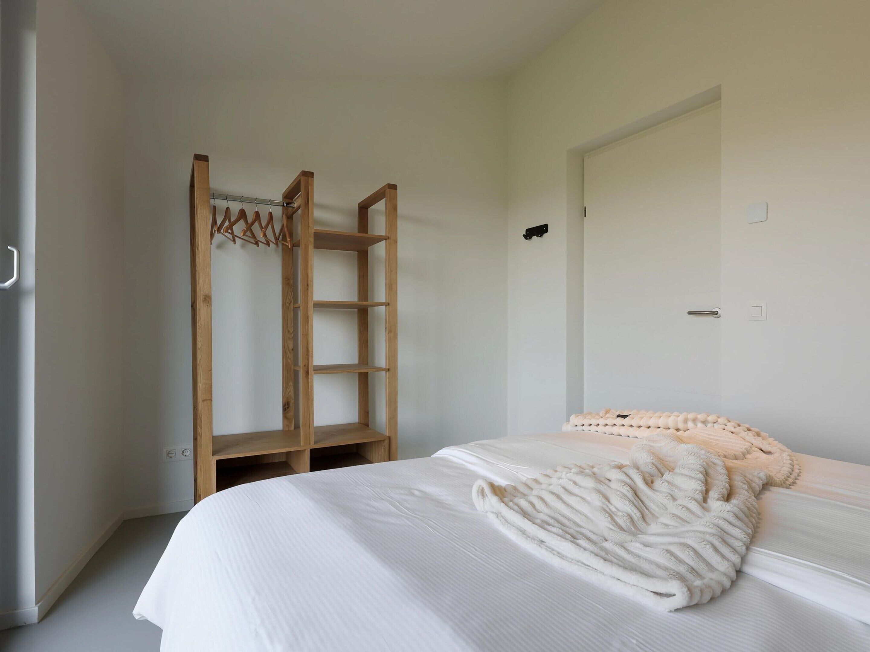 Una camera da letto con un letto, una scala in legno e una porta bianca.