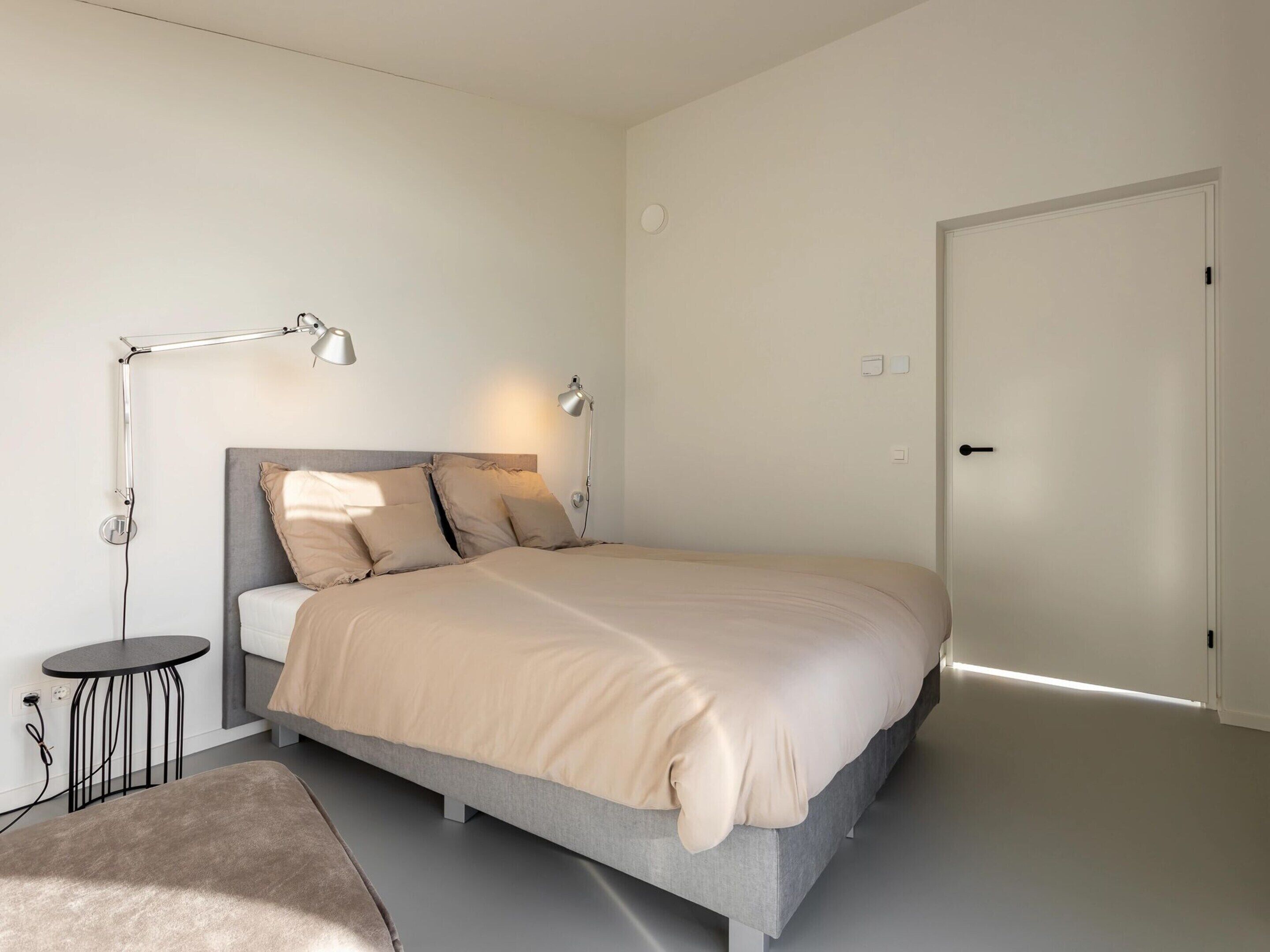 Ein modernes Schlafzimmer mit einem Bett, Nachttischen und einer Tür.