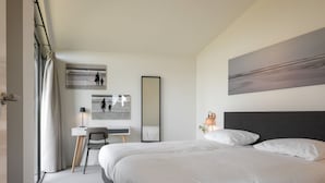 A modern hotel room with a large bed, a desk, and a chair. - Cottage in Wissenkerke Near Het Bokkegat (Wissenkerke)